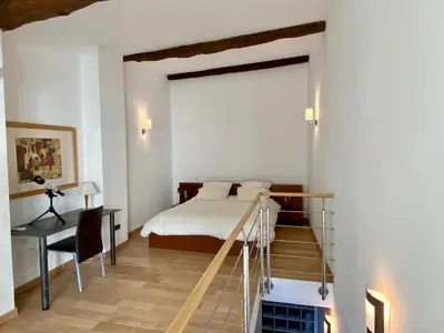 a bedroom with a bed and a desk and a staircase at Gite La Grange, climatisée, vue sur le château de Peyrepertuse in Rouffiac-des-Corbières