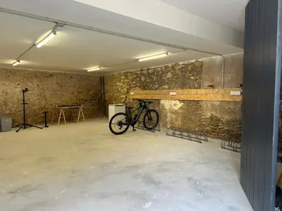 a bike parked in a room with a stone wall at Le Loft du Canal du midi & son garage Vélos-Capestang in Capestang