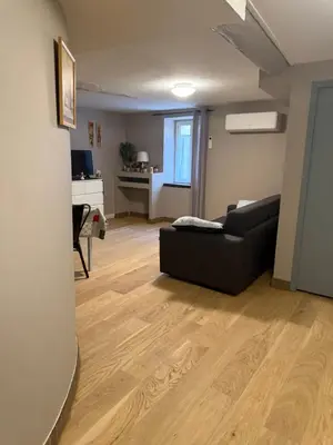 a living room with a black couch and a desk at Appartement détente dans les corbières in Conilhac-Corbières
