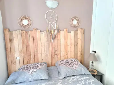 a bed with a wooden headboard and two mirrors at La parenthèse Carcassonnaise - 4 voyageurs - Terrasse - Proche cité médiévale in Carcassonne
