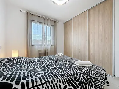 a black and white bed in a room with a window at La Caminade - Maison Neuve - Climatisation et Wifi in Saint-André-de-Roquelongue