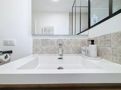 a white bathroom with a sink and a mirror at La Caminade - Maison Neuve - Climatisation et Wifi in Saint-André-de-Roquelongue