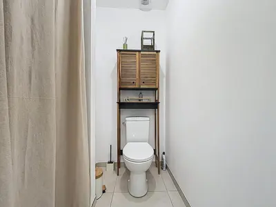 a bathroom with a toilet and a wooden cabinet at La Caminade - Maison Neuve - Climatisation et Wifi in Saint-André-de-Roquelongue
