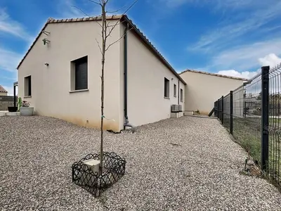 a small tree in a cage in front of a building at La Caminade - Maison Neuve - Climatisation et Wifi in Saint-André-de-Roquelongue