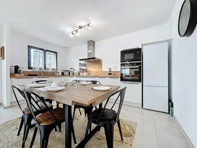 a kitchen with a wooden table and some chairs at La Caminade - Maison Neuve - Climatisation et Wifi in Saint-André-de-Roquelongue
