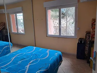 a bedroom with a bed and two windows at Villa Pierrot in Portel-des-Corbières