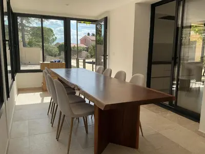 a dining room with a wooden table and chairs at Entre sel et ciel 2 maisons 2 caractères 1 piscine 1 boulodrome 2 ascenseurs in Peyriac-de-Mer