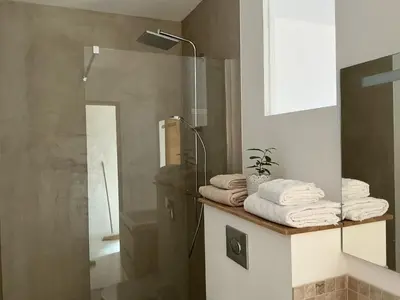 a bathroom with a shower and towels on a counter at Entre sel et ciel 2 maisons 2 caractères 1 piscine 1 boulodrome 2 ascenseurs in Peyriac-de-Mer