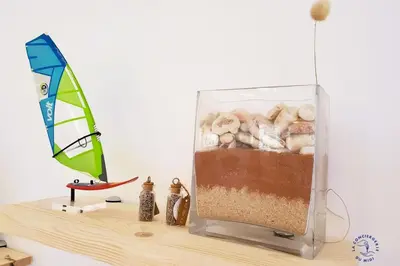 a wooden shelf with a sail and a container of sand and seashells at La Saline maison familiale avec jardin in Lapalme