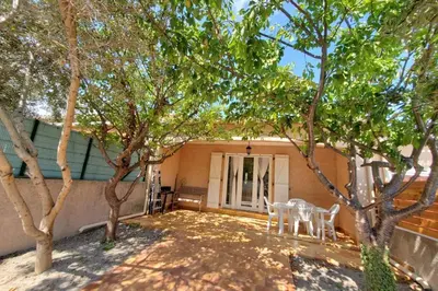 a patio with two chairs and trees in front of a house at Le Salvador paisible maisonette pour 4 in Sigean