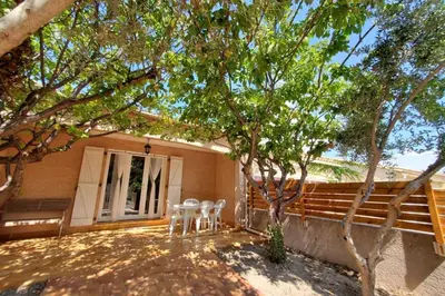 a patio with two chairs and a table in front of a house at Le Salvador paisible maisonette pour 4 in Sigean