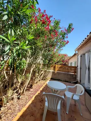 a patio with a table and two chairs and flowers at Le Salvador paisible maisonette pour 4 in Sigean