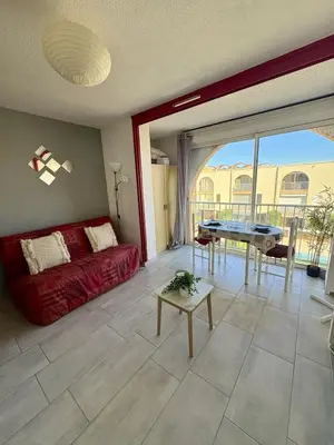 a living room with a red couch and a table at Studio à deux pas du port avec piscine in Gruissan