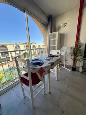 a table and chairs in a room with a balcony at Studio à deux pas du port avec piscine in Gruissan