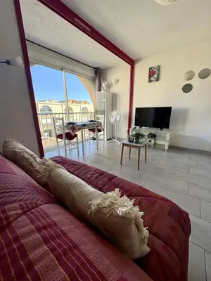 a bedroom with a bed and a living room with a view at Studio à deux pas du port avec piscine in Gruissan