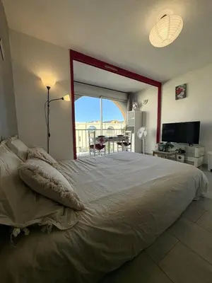 a bedroom with a large bed with a large window at Studio à deux pas du port avec piscine in Gruissan
