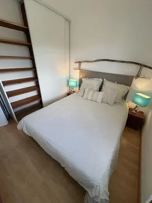 a bedroom with a large white bed with two lamps at Appartement cosy vue mer avec terrasse in Gruissan