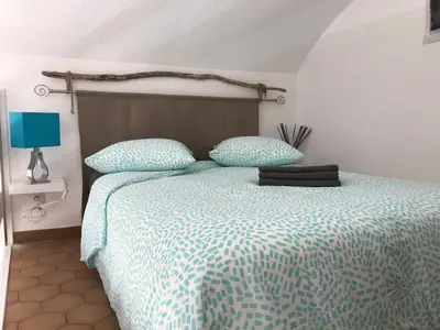 a bedroom with a bed with a blue and white comforter at Appartement cosy vue mer avec terrasse in Gruissan