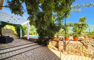 a backyard with a stone wall and a white pergola at Gorgeous Home In Villespassans in Villespassans