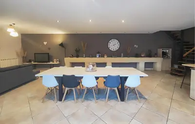 a table and chairs in a room with a clock on the wall at Stunning Home In Puisserguier in Puisserguier