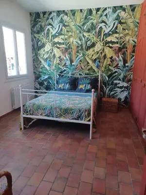a bedroom with a bed with a tropical wallpaper at Maison Sol Air in Montazels