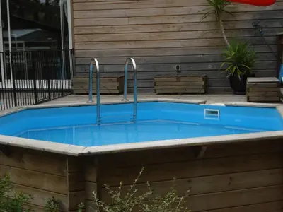a swimming pool with two faucets in front of a house at Maison dans un écrin de verdure in Sorèze
