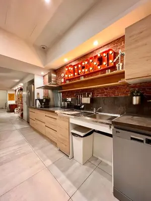 a large kitchen with wooden cabinets and a brick wall at Loft jacuzzi à 8 min des Grands Buffets et du centre-ville in Narbonne