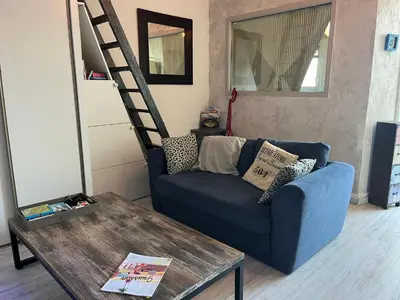 a living room with a blue couch and a ladder at Gruissan : T2 Climat. et Parking Proche Village - FR-1-796-96 in Gruissan