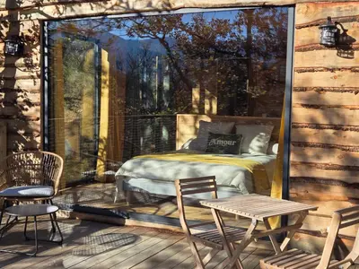a room with a bed and chairs on a porch at La parenthèse in Ansignan