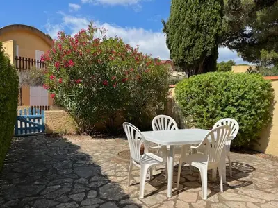 a white table and four chairs in front of a bush at Gruissan - Villa 6 Pers - Terrasses - Secteur Calme - FR-1-796-102 in Gruissan