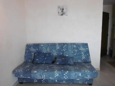 a blue couch with pillows on it in a room at Studio à 50m de la Plage du Grazel avec Parking - FR-1-796-104 in Gruissan