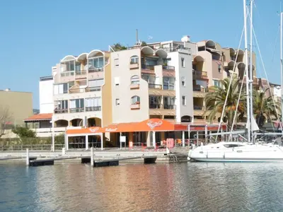 a white boat docked in front of a building at Studio Coquet 2/3 Pers au Cœur de Gruissan - FR-1-796-99 in Gruissan