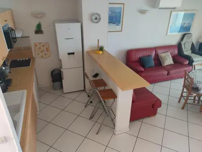 a kitchen with a table and a red couch in a room at Villa T4 Gruissan avec Vue Mer, Climatisée, 80m2, Plage à 50m, 6 Pers. - FR-1-796-100 in Gruissan