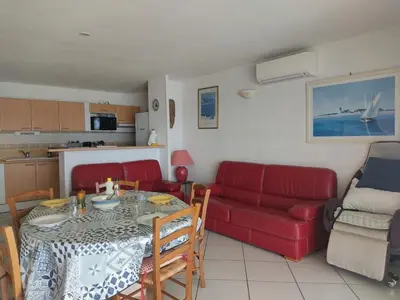 a living room with a table and a red couch at Villa T4 Gruissan avec Vue Mer, Climatisée, 80m2, Plage à 50m, 6 Pers. - FR-1-796-100 in Gruissan