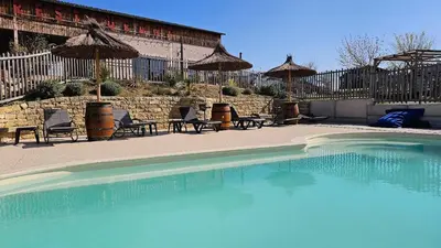 a large swimming pool with chairs and umbrellas at Tente Out of Africa in Alzonne