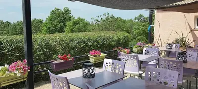 a patio with tables and chairs and flowers on a balcony at Tente Out of Africa in Alzonne