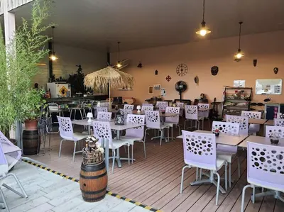 a restaurant with white tables and chairs in a room at Tente Out of Africa in Alzonne