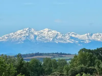 a snow covered mountain range with trees in the foreground at Tente Out of Africa in Alzonne
