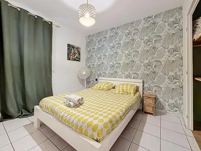 a bedroom with a bed with a yellow and white blanket at Le Brooklyn - Appartement rez de chaussée - Wifi in Narbonne