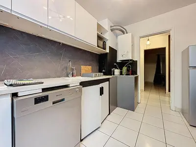 a kitchen with white cabinets and white appliances at Le Brooklyn - Appartement rez de chaussée - Wifi in Narbonne