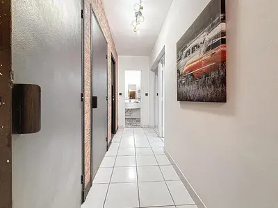 a hallway with a tile floor and a painting on the wall at Le Brooklyn - Appartement rez de chaussée - Wifi in Narbonne