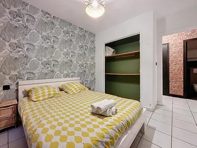 a bedroom with a bed with a yellow and white comforter at Le Brooklyn - Appartement rez de chaussée - Wifi in Narbonne