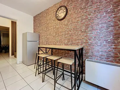 a brick wall with a table and a clock on it at Le Brooklyn - Appartement rez de chaussée - Wifi in Narbonne