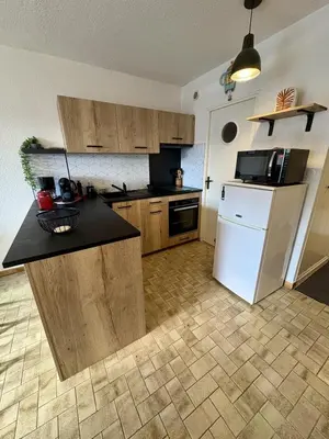 a kitchen with wooden cabinets and a white refrigerator at Studio sur le port avec piscine & terrasse in Gruissan