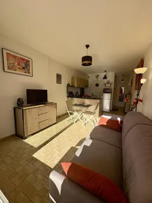 a living room with a couch and a kitchen at Studio sur le port avec piscine & terrasse in Gruissan