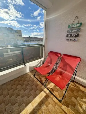a red chair sitting in front of a window at Studio sur le port avec piscine & terrasse in Gruissan