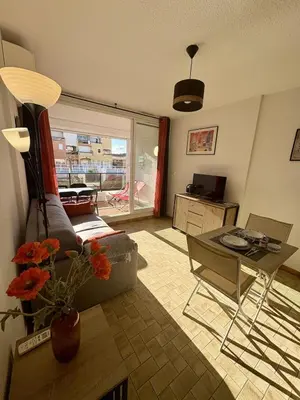 a living room with a couch and a table at Studio sur le port avec piscine & terrasse in Gruissan