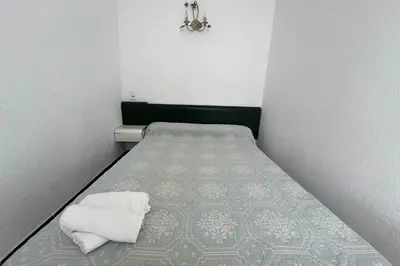 a small bedroom with a bed with a green headboard at Nice Apt close to the beaches of Port-la-Nouvelle in Port-la-Nouvelle