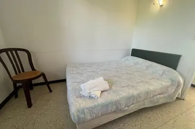 a small bedroom with a bed and a chair at Nice Apt close to the beaches of Port-la-Nouvelle in Port-la-Nouvelle
