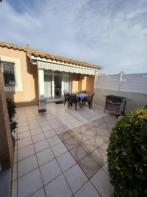 a patio with a table and chairs on a house at Pavillon avec piscine à deux pas de la plage in Gruissan